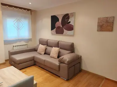 a living room with a brown couch in a room at Apartamento Vieiro con plaza garaje gratis in Santiago de Compostela