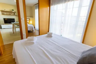 a bedroom with a white bed with two towels on it at Apartagal-Ed Batel Foz in Foz