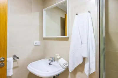 a white bathroom with a sink and a mirror at Apartagal-Ed Batel Foz in Foz