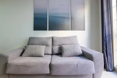 a couch in a living room with a painting on the wall at Apartagal-Ed Batel Foz in Foz