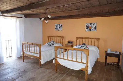 two beds in a room with wooden floors at Los Polvazares in Castrillo De Los Polvazares