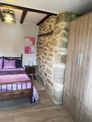 a bedroom with a bed in a stone wall at Carballo Alenza in Sistín
