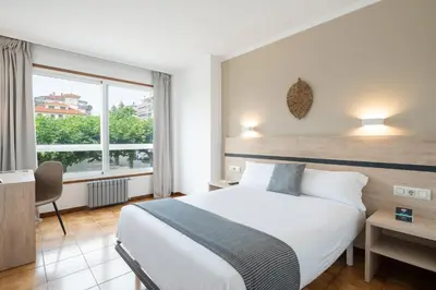 a bedroom with a large white bed and a window at Hotel Alda Camiño Inglés in Ordes