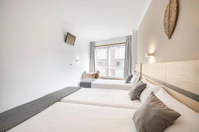 a bedroom with two beds and a window at Hotel Alda Camiño Inglés in Ordes