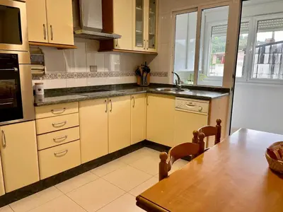 a kitchen with white cabinets and a wooden table at Apartamento en A Pontenova in A Pontenova