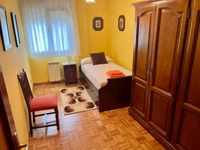 a bedroom with a bed and a cabinet and a chair at Apartamento en A Pontenova in A Pontenova