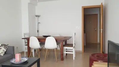a living room with a wooden table and white chairs at Agradable apartamento a 2 minutos de la playa in Ares