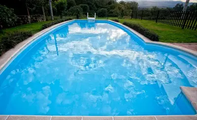 a large pool with blue water in a yard at Casa A Pedriña in Amés
