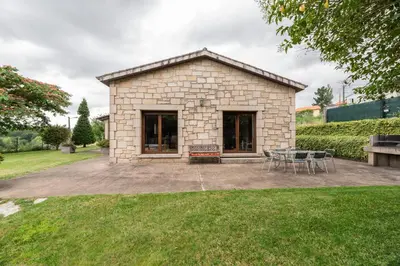 a stone house with a table and chairs in a yard at Casa A Pedriña in Amés