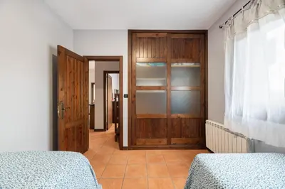 a bedroom with two beds and a wooden door at Casa A Pedriña in Amés