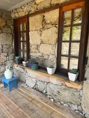 a stone house with windows and potted plants on a porch at Casa Las Piedras in Padrenda