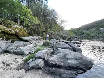 a person standing on some rocks near a body of water at Casa Las Piedras in Padrenda