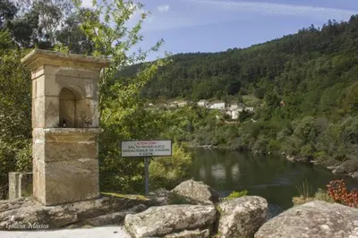 a stone building with a sign next to a river at Casa Las Piedras in Padrenda