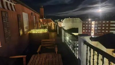 a balcony with two chairs and lights on a building at ÁTICO DUPLEX CREDENCIAL in Sarria