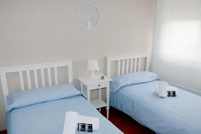 a bedroom with two beds and a table with a lamp at ÁTICO DUPLEX CREDENCIAL in Sarria