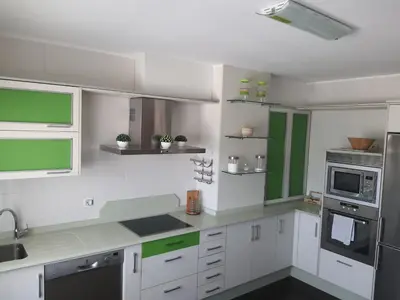 a kitchen with white cabinets and green accents at ÁTICO DUPLEX CREDENCIAL in Sarria