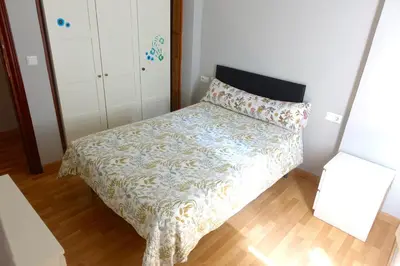 a small bedroom with a bed with a floral bedspread at Yellow Door 2 in Ponferrada