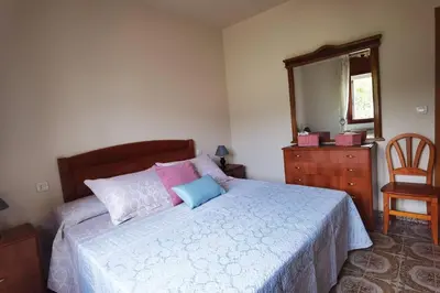 a bedroom with a bed and a dresser and a mirror at Foz Acogedora casa familiar in Barrosa