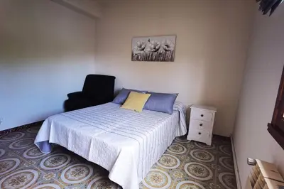 a bedroom with a bed and a black chair at Foz Acogedora casa familiar in Barrosa