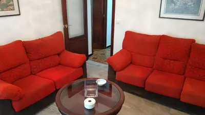 a living room with two red couches and a table at Piso en centro urbano de Puentedeume con terraza in Puentedeume