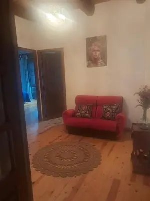a red couch in a living room with a wooden floor at CASA MAGUETO 2 noches mínimo in Toreno
