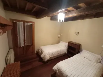 a bedroom with two beds and a window and wooden floors at Casa de Abril 2 in San Cristóbal de Valdueza