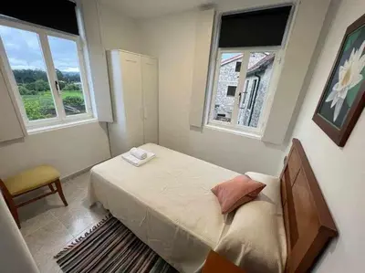 a small bedroom with a bed and two windows at Apartamento A in Irijoa