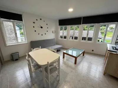 a living room with a table and a clock on the wall at Apartamento A in Irijoa