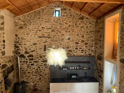 a kitchen with a stone wall with a chandelier at Casa Fogar do Ulla in Vedra