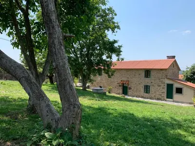 an old stone house with a tree in the foreground at Casa Fogar do Ulla in Vedra