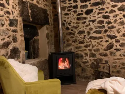 a fireplace in a stone room with a yellow chair at Casa Fogar do Ulla in Vedra