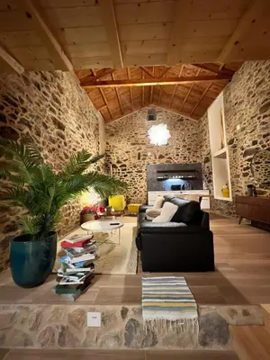 a living room with a black couch and a stone wall at Casa Fogar do Ulla in Vedra