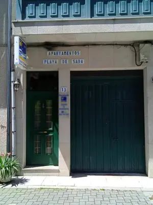 a green garage door in front of a building at Céntrico Estudio in Sada