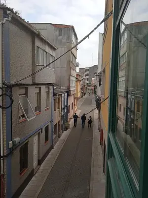two people walking down a street between two buildings at Céntrico Estudio in Sada