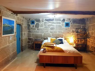 a bedroom with a bed in a stone wall at A aira da xoaniña in Allariz