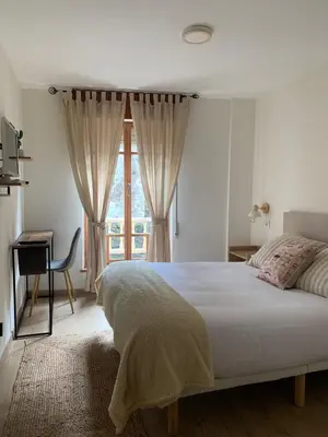 a bedroom with a bed and a desk and a window at Pensión Cantabrico in Navia