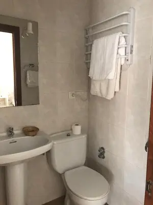 a bathroom with a white toilet and a sink at Pensión Cantabrico in Navia