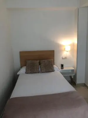 a bedroom with a large bed with a nightstand and a bed sidx sidx sidx at Pensión Cantabrico in Navia
