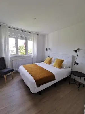 a bedroom with a large bed and a chair at Apartamentos Seijo in Villalba