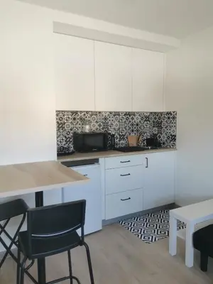 a kitchen with white cabinets and a table and chairs at Apartamentos Seijo in Villalba