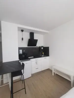 a kitchen with white cabinets and a table and a bench at Apartamentos Seijo in Villalba
