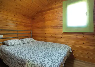 a bedroom with a bed in a wooden cabin at Cabañas El Ruso in Galende