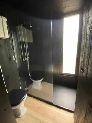 a black bathroom with a toilet and a window at A Leira 116 Cabañas de diseño in Sarria