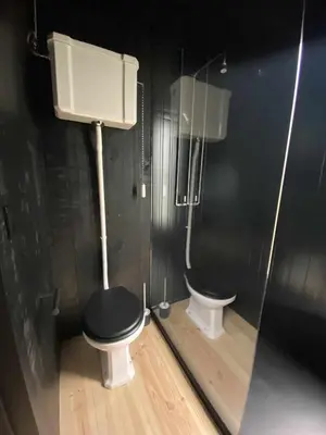 a bathroom with a toilet with a black wall at A Leira 116 Cabañas de diseño in Sarria