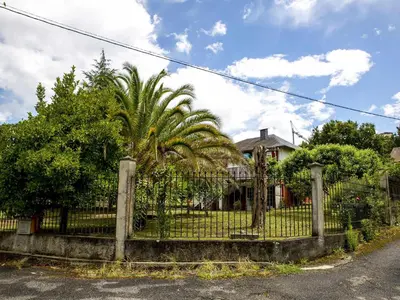 a fence in front of a house with a palm tree at A Casiña - Casa Rural en la Ribeira Sacra, Galicia in Ourense