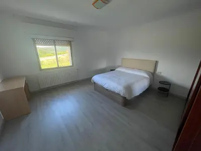 a white bedroom with a bed and a window at LA RATONERA in Podentes