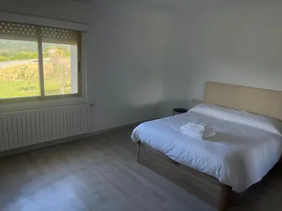 a white bedroom with a bed and a window at LA RATONERA in Podentes