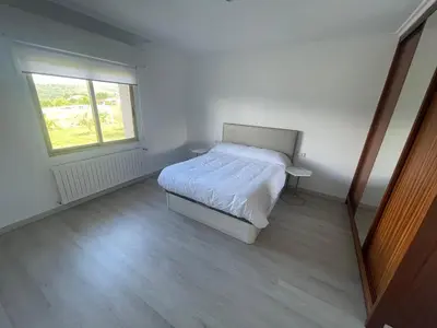 a white bedroom with a bed and a window at LA RATONERA in Podentes