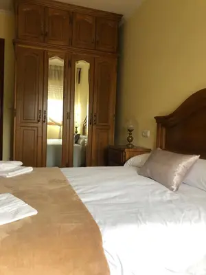 a bedroom with a large white bed with a wooden headboard at FIFA in Arzúa