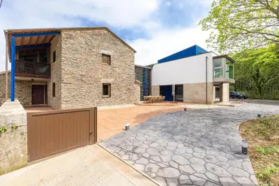 a house with a stone driveway in front of a building at A Casa do Souto, Santiago de Compostela in Sigüeiro